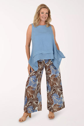 Woman wearing a blue sleeveless top and patterned pants on a white background