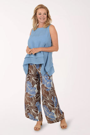 Woman wearing a blue sleeveless top and patterned pants on a white background