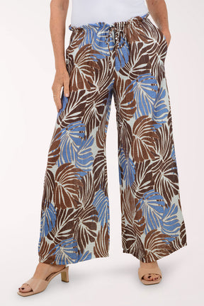 Tropical leaf patterned pants worn by a person on a white background