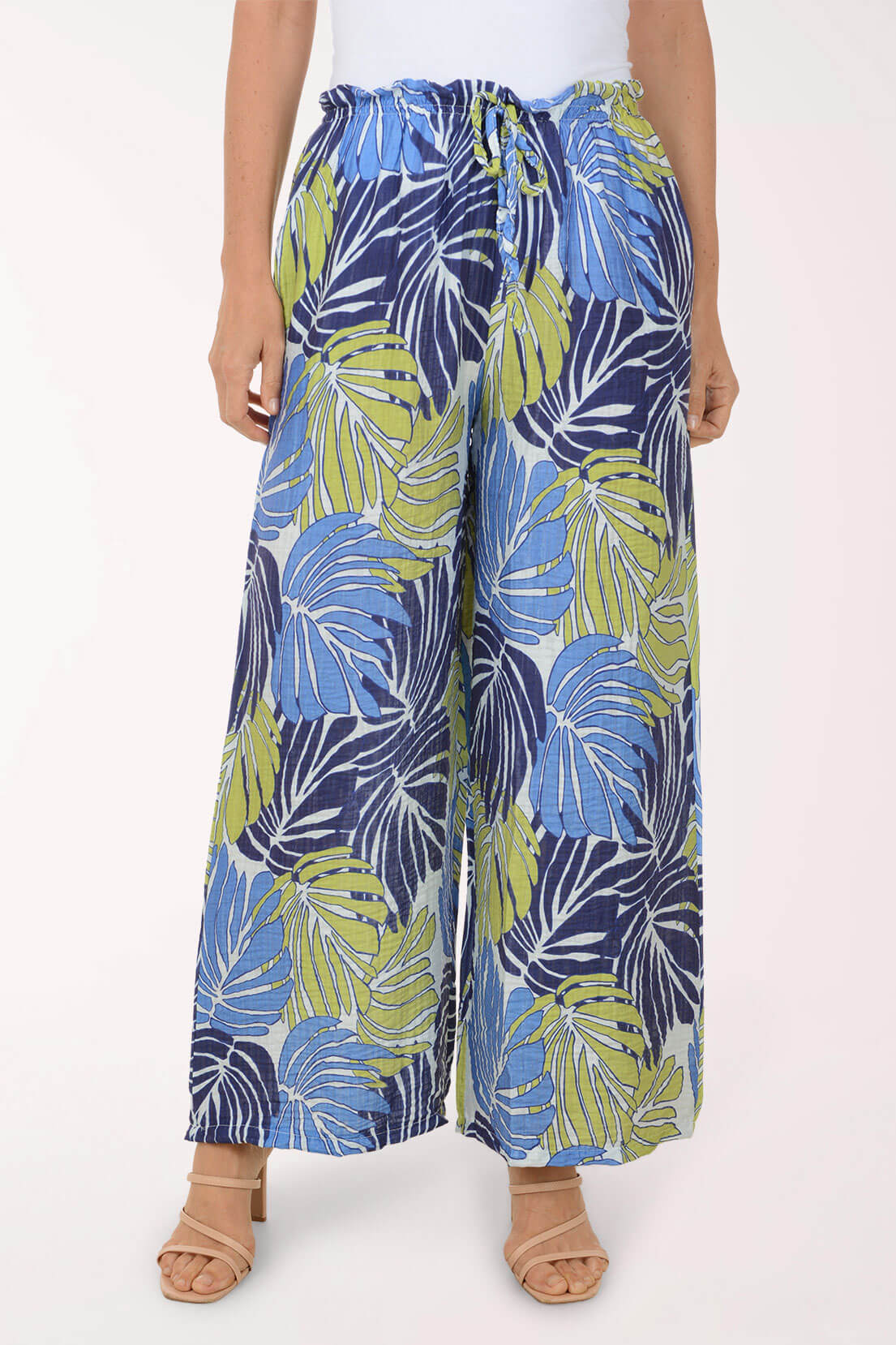 Person wearing blue and green leaf-patterned wide-leg pants on a white background