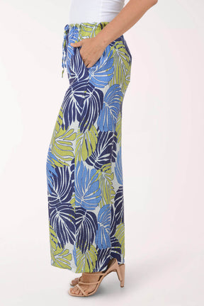 Tropical leaf patterned pants worn by a person on a white background