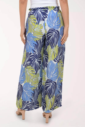Tropical leaf patterned pants worn by a person on a white background