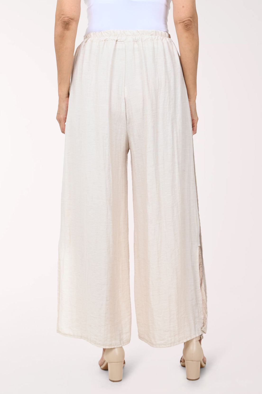 Person wearing white wide-leg pants on a white background
