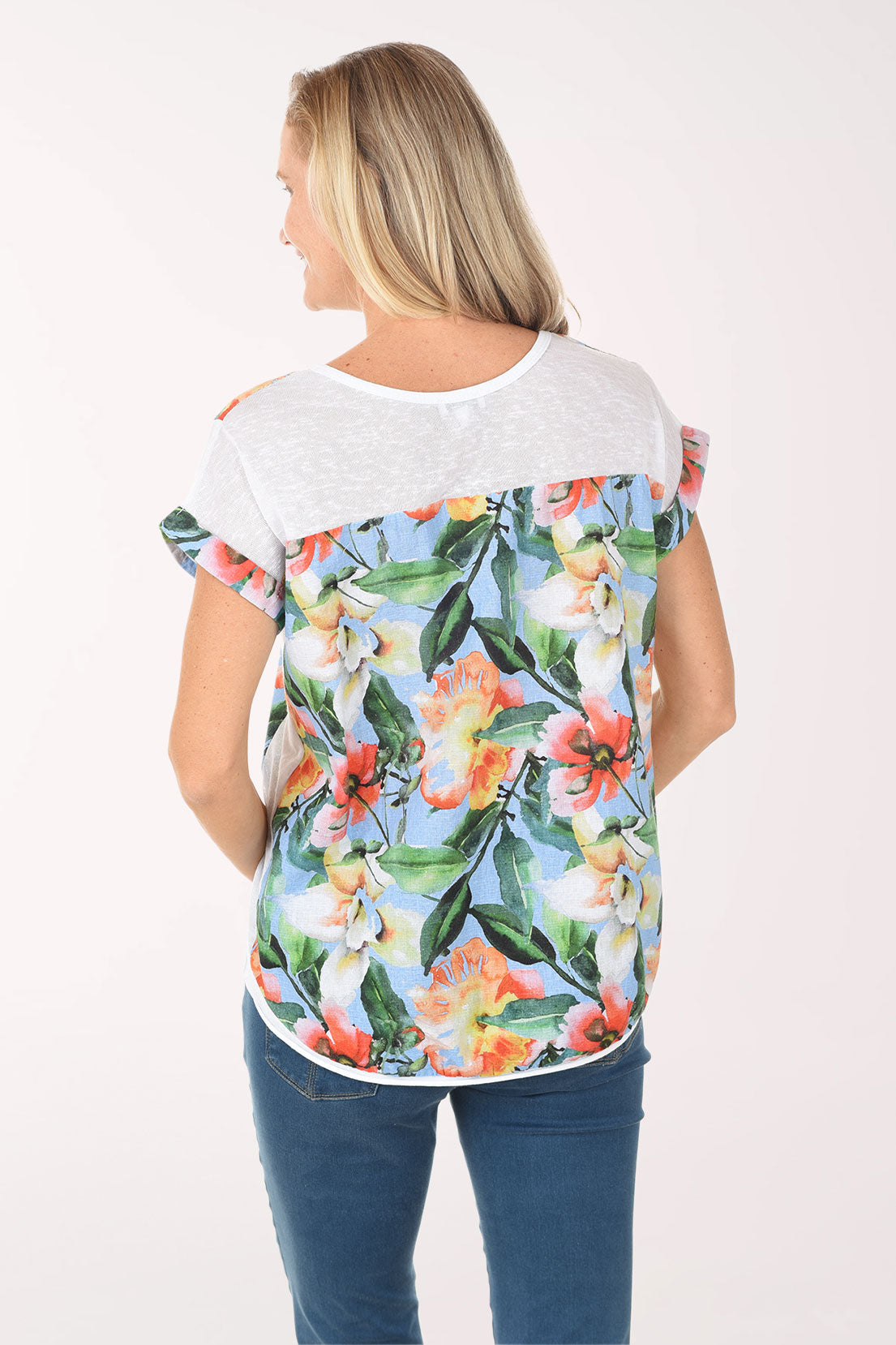Woman wearing a colorful floral t-shirt and blue jeans on a white background