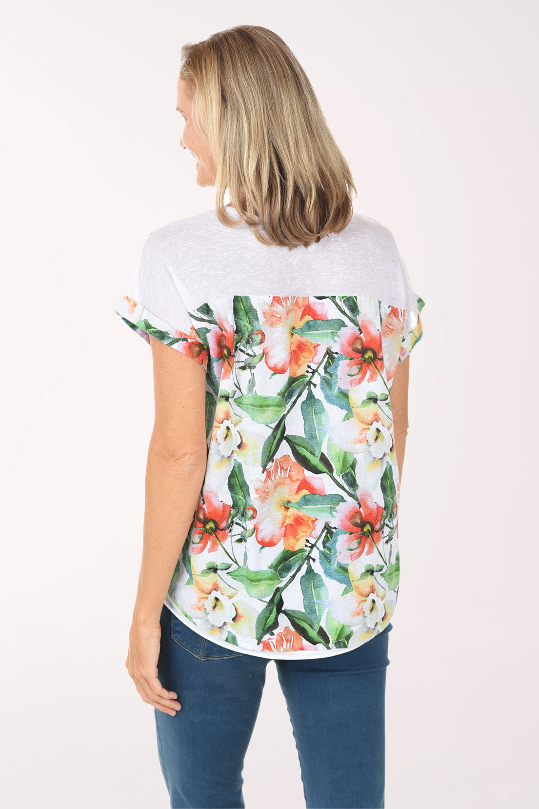 Woman wearing a white t-shirt with floral design and blue jeans on a white background