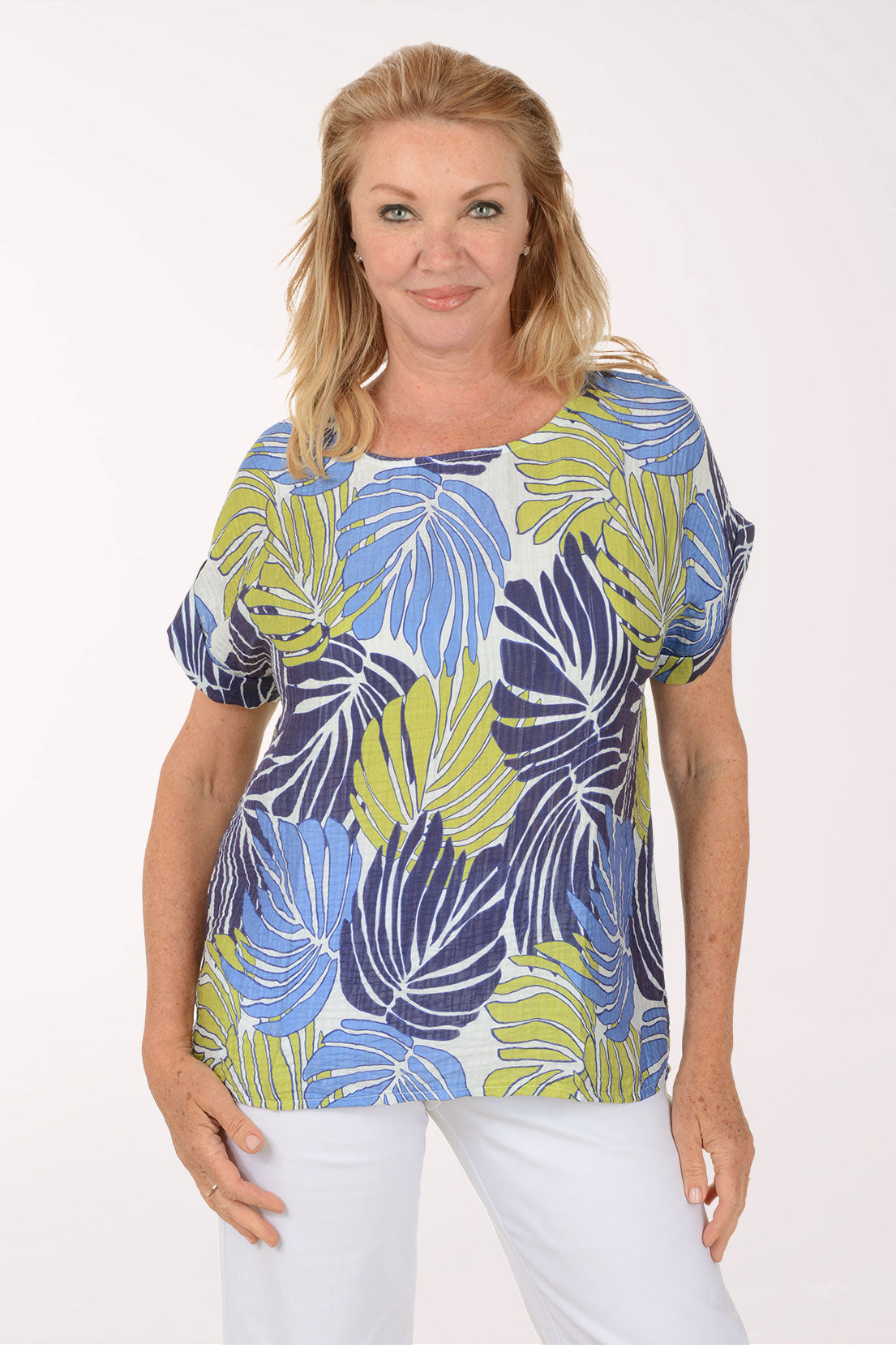 Woman wearing a colorful leaf-patterned top on a white background