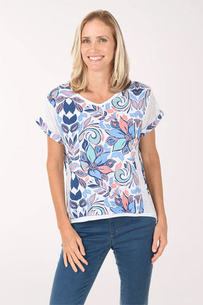 Woman wearing a colorful patterned top and blue jeans on a white background