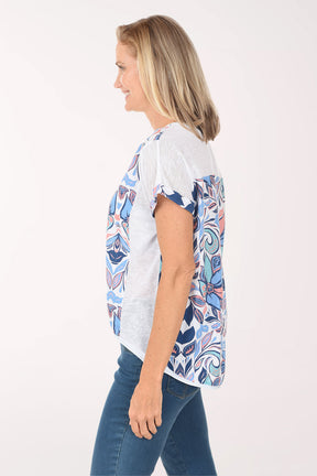 Woman wearing a colorful patterned top and blue jeans on a white background