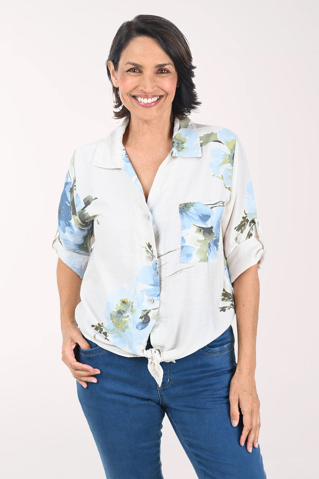 Woman wearing a beige floral blouse with rolled-up sleeves on a white background