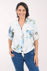 Woman wearing a beige floral blouse with rolled-up sleeves on a white background