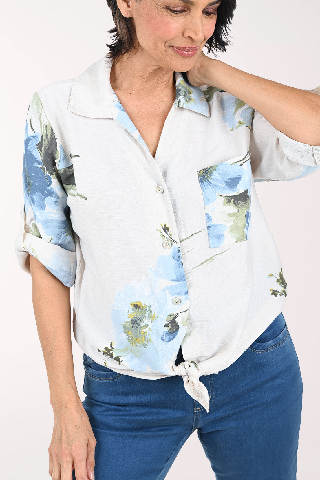 Woman wearing a beige floral blouse with rolled-up sleeves on a white background