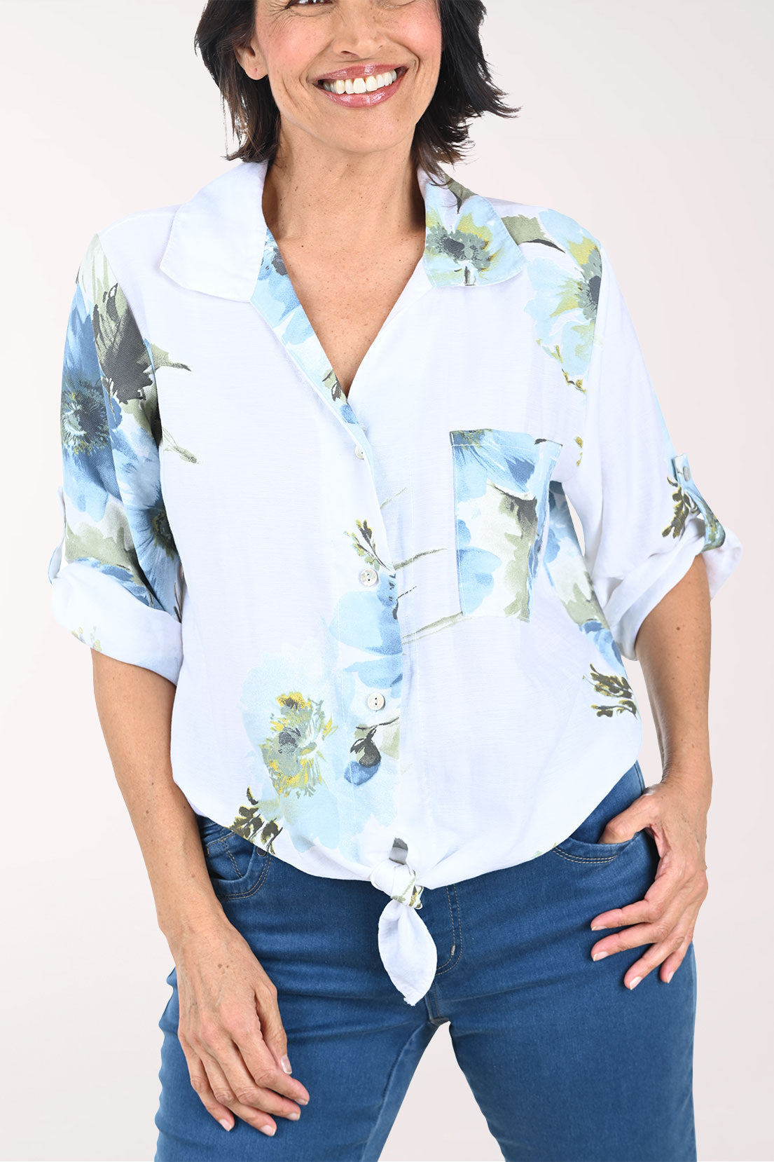 Woman wearing a white floral blouse with rolled-up sleeves on a white background