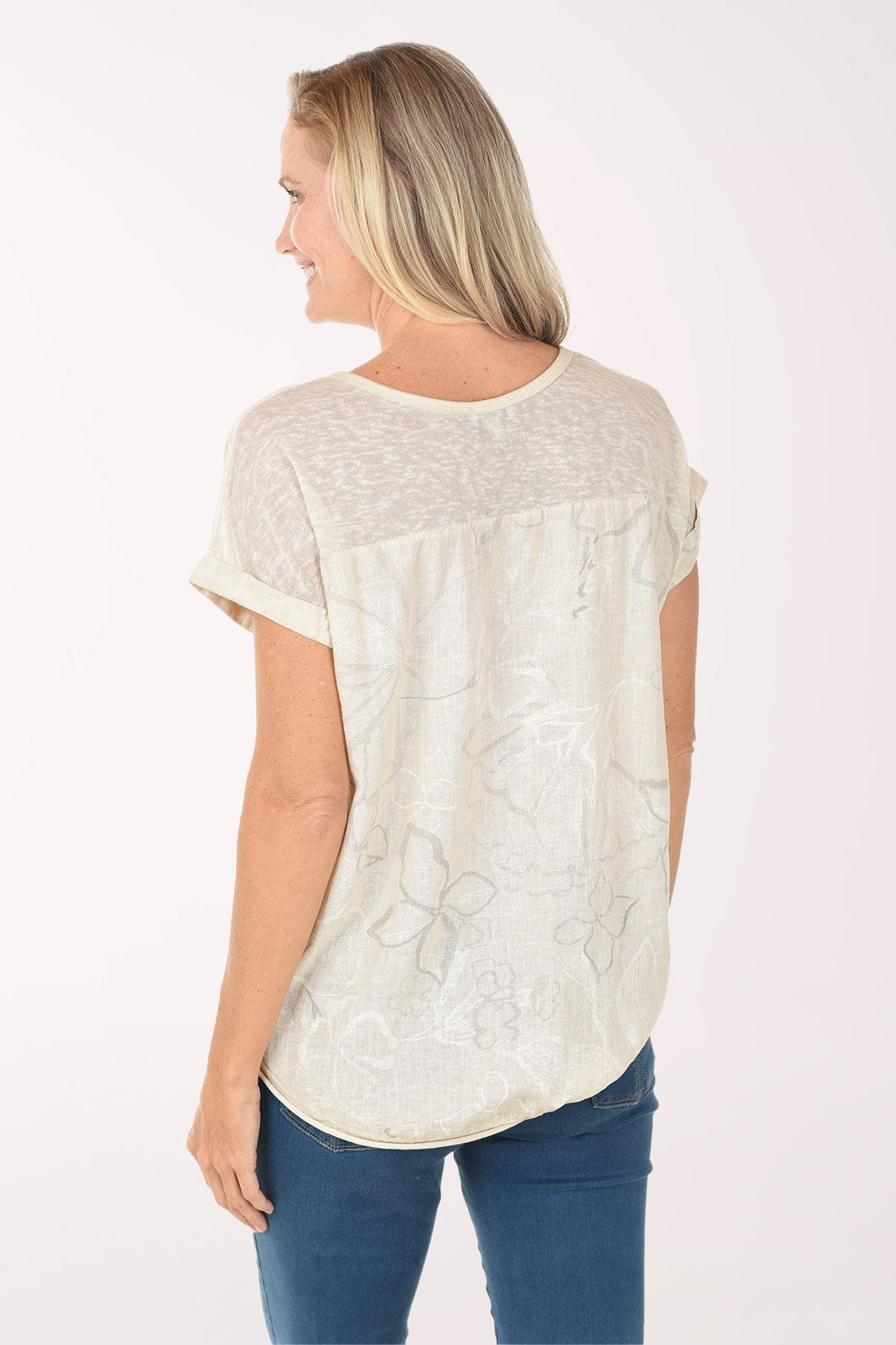 Woman wearing a beige lace top and blue jeans on a white background