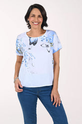 Woman wearing a light blue t-shirt with butterfly design on a white background