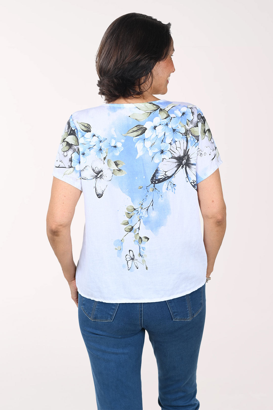 Woman wearing a light blue t-shirt with butterfly design on a white background