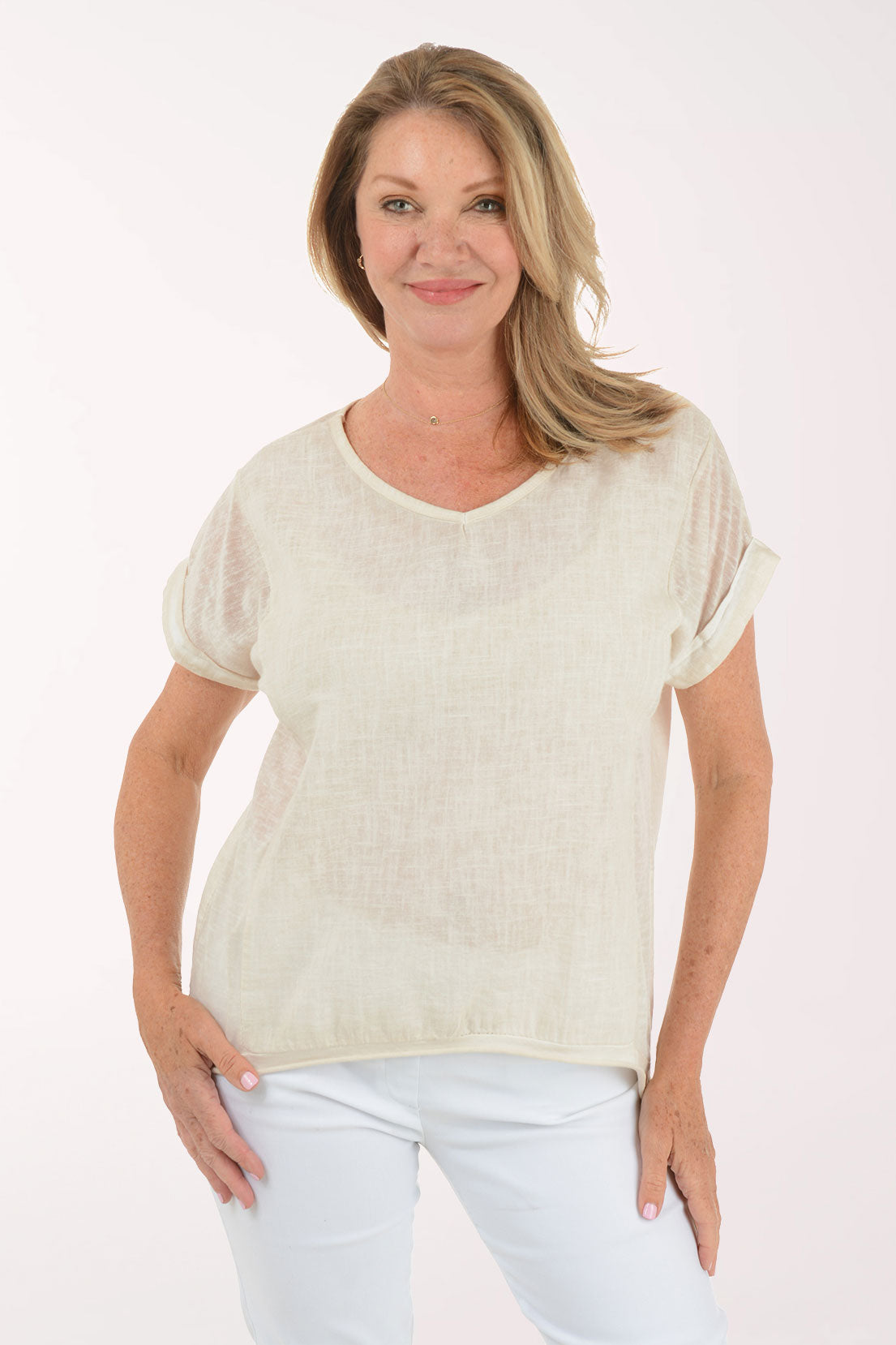 Woman wearing a beige t-shirt and light blue jeans on a white background
