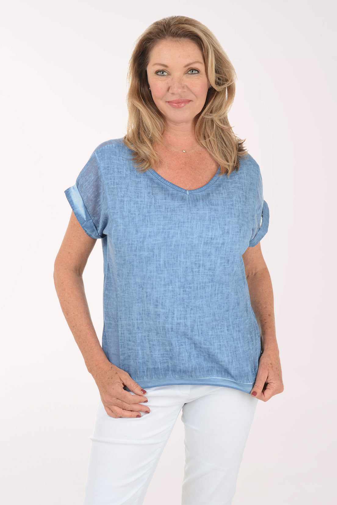 Woman wearing a blue top and white pants on a white background