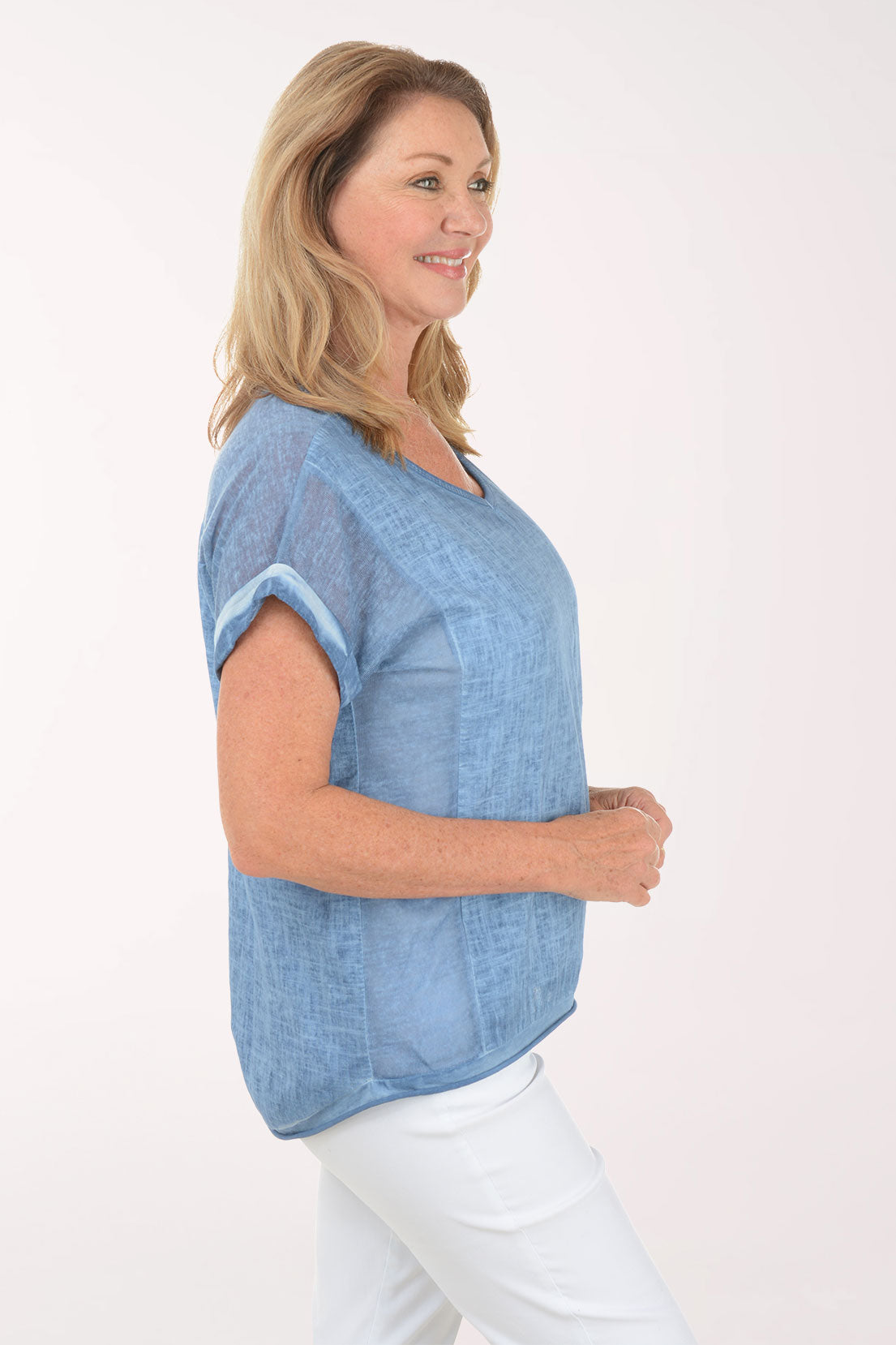 Woman wearing a blue top and white pants on a white background