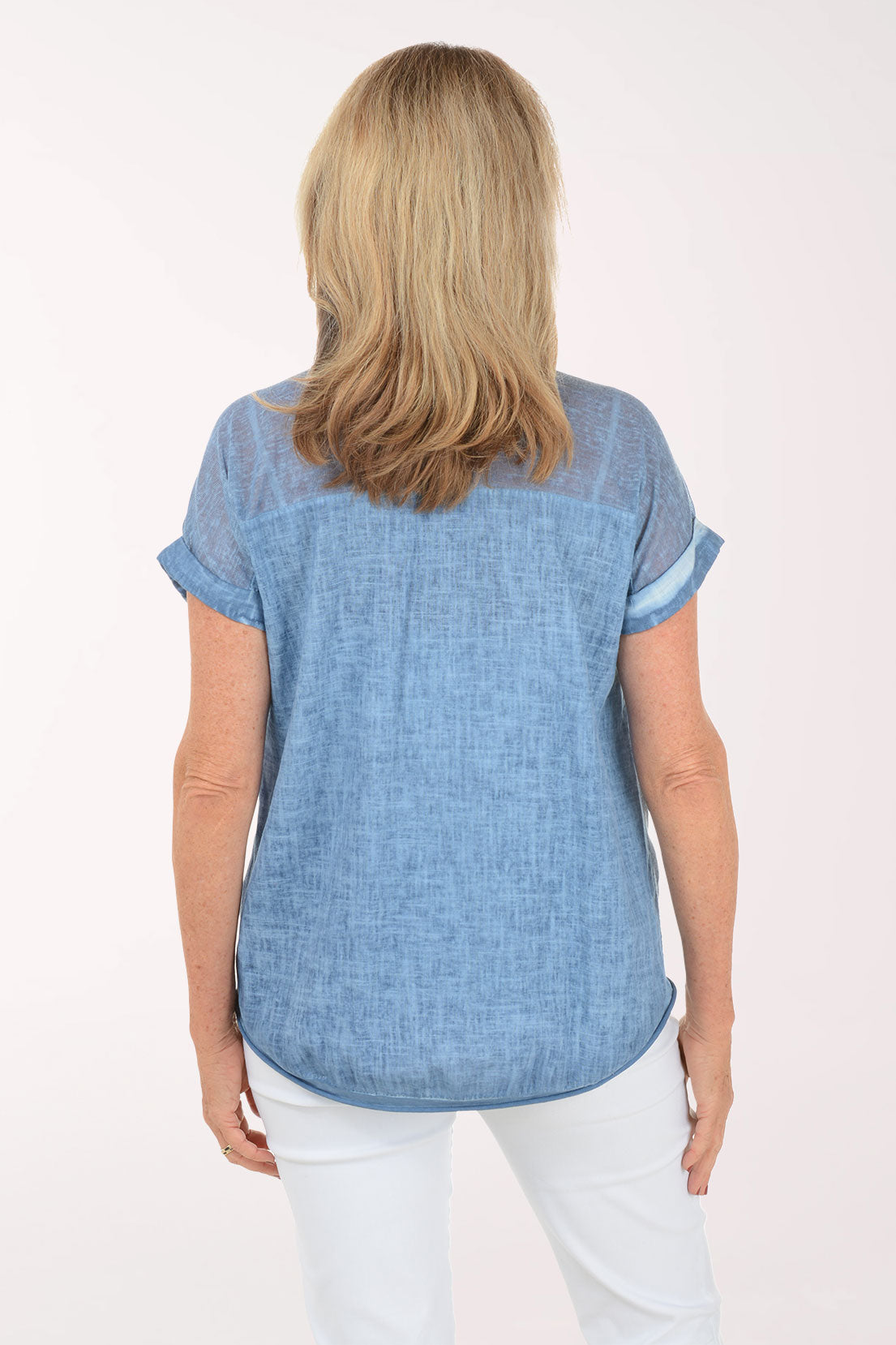 Woman wearing a blue top and white pants on a white background