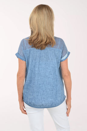 Woman wearing a blue top and white pants on a white background