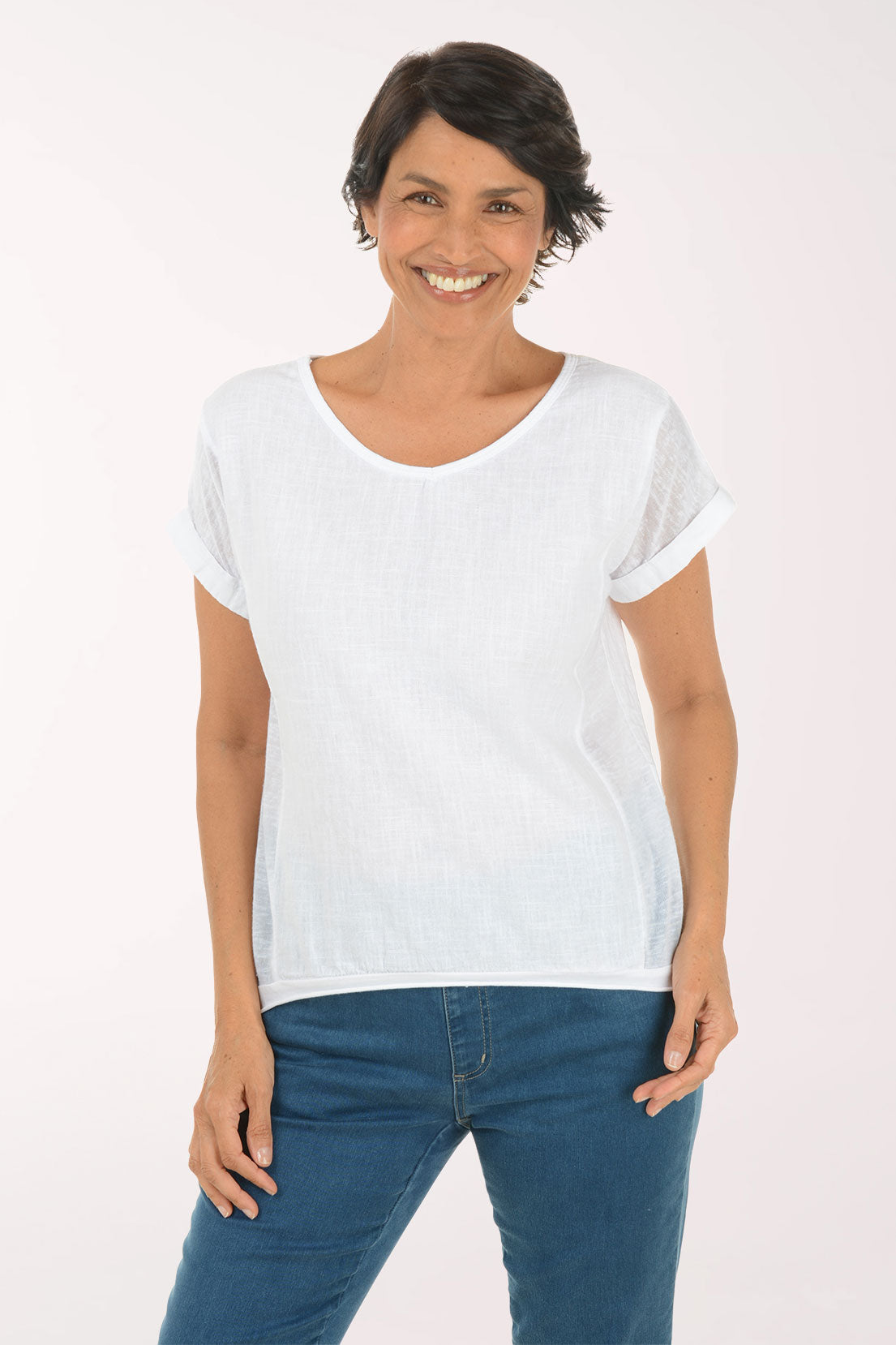 Woman wearing a white t-shirt and blue jeans on a light pink background