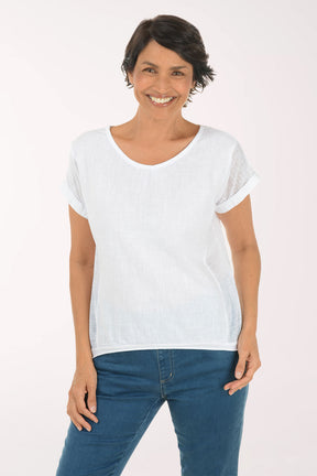Woman wearing a white t-shirt and blue jeans on a light pink background