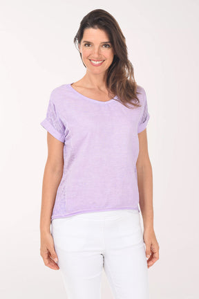 Woman wearing a light purple t-shirt and white pants on a white background