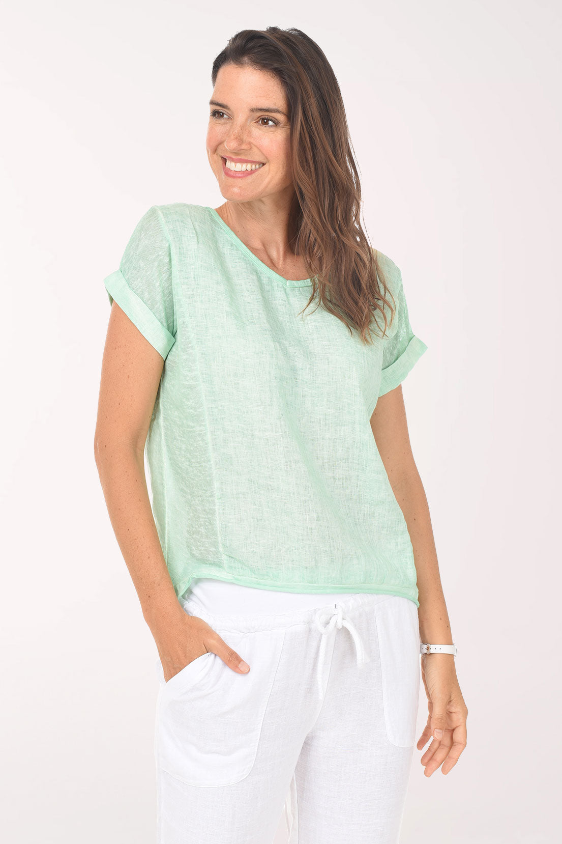 Woman wearing a light green top and white pants on a white background