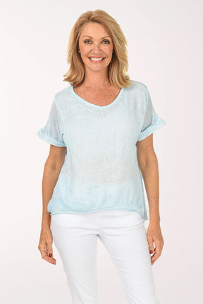 Woman wearing a light blue gradient top and white pants on a white background