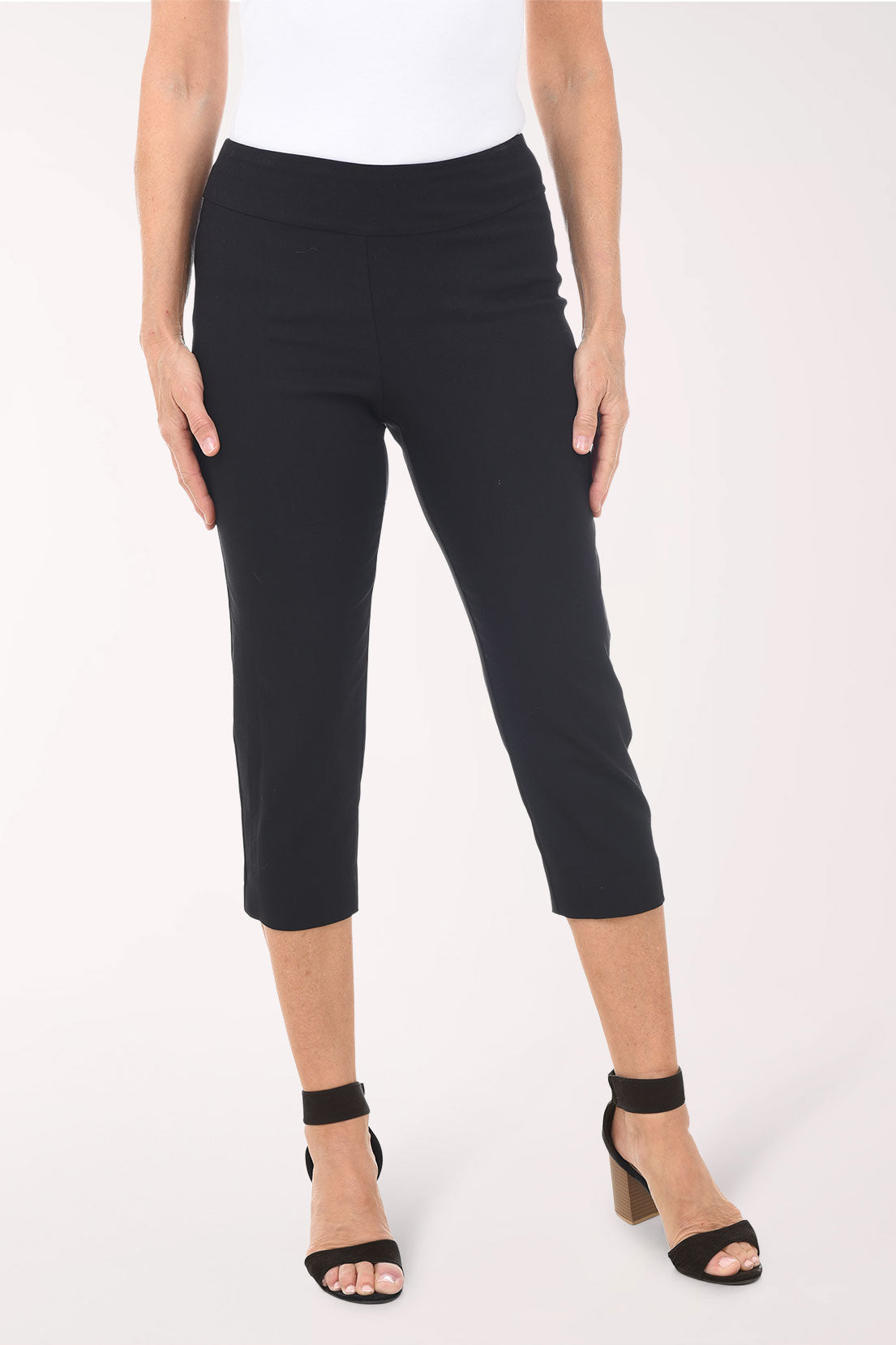 Person wearing black capri pants on a white background