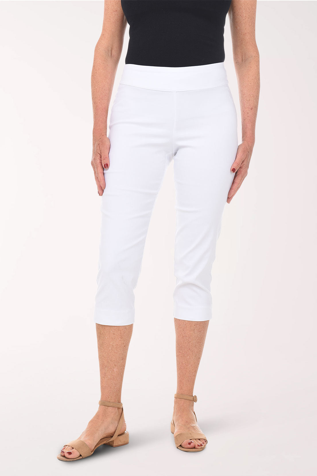 Person wearing white capri pants and a black top on a white background
