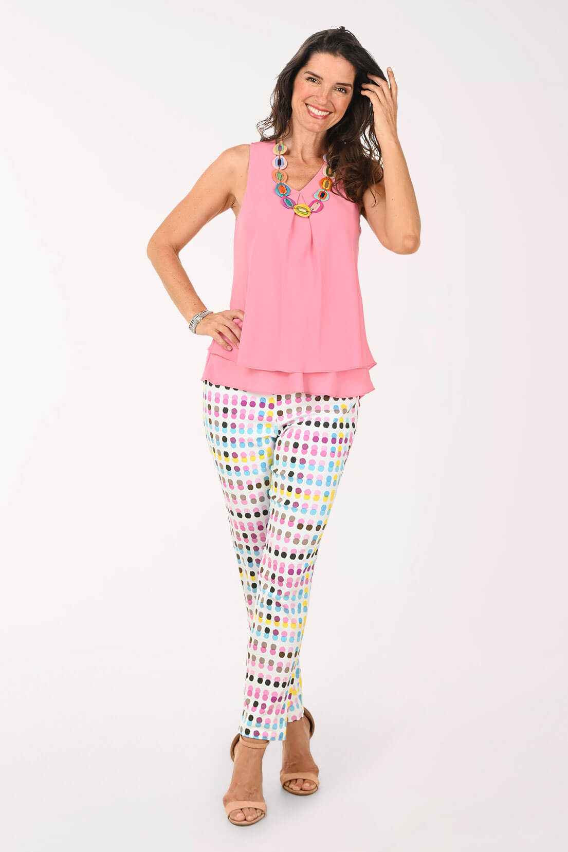 Woman wearing a pink top and colorful polka dot pants on a white background
