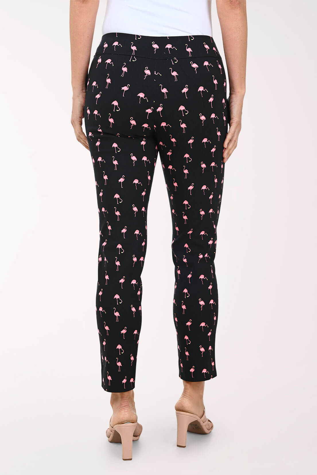 Black pants with pink flamingo pattern worn by a person on a white background