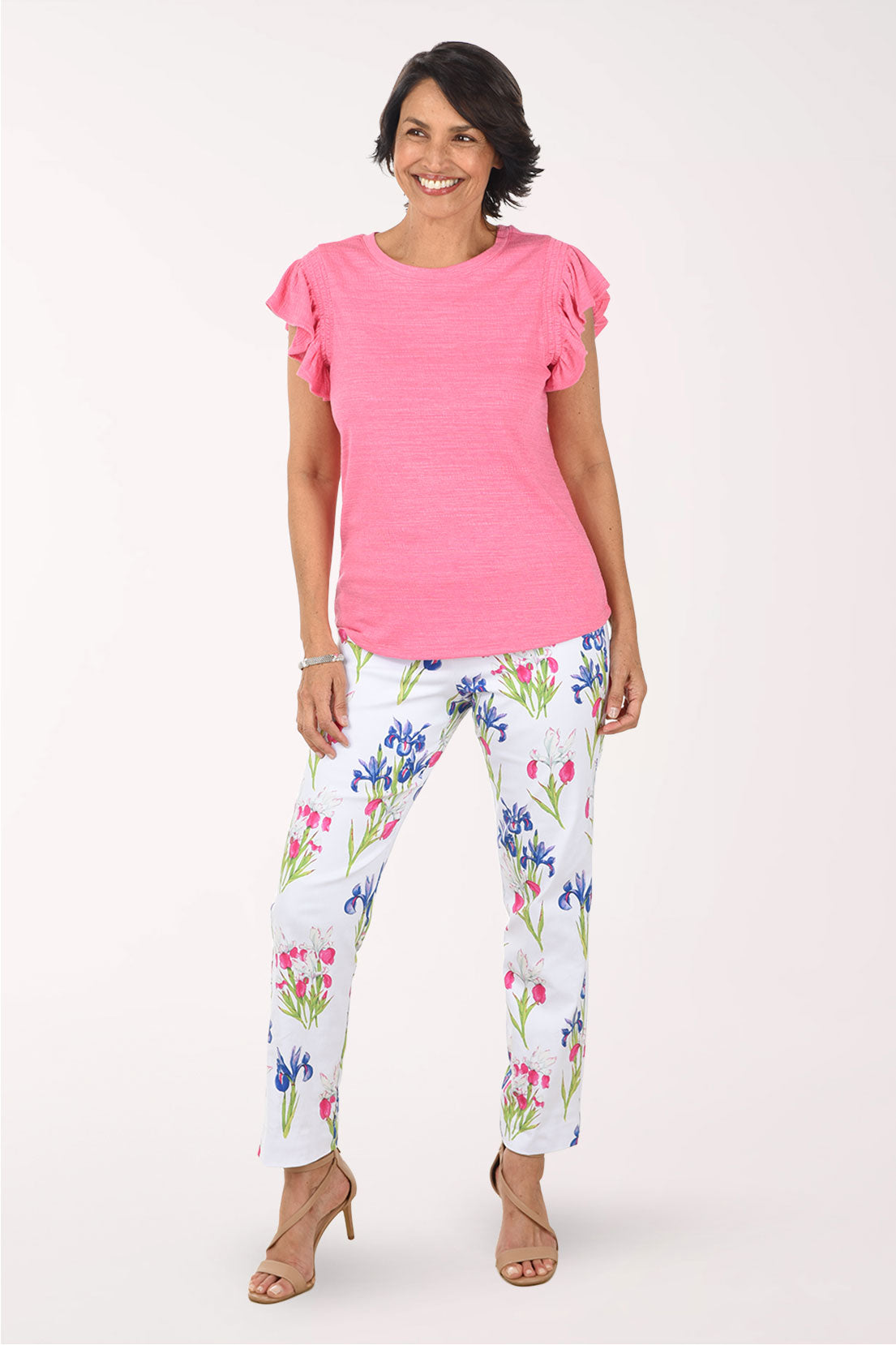 Woman wearing a pink top and floral pants on a white background