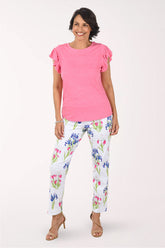 Woman wearing a pink top and floral pants on a white background