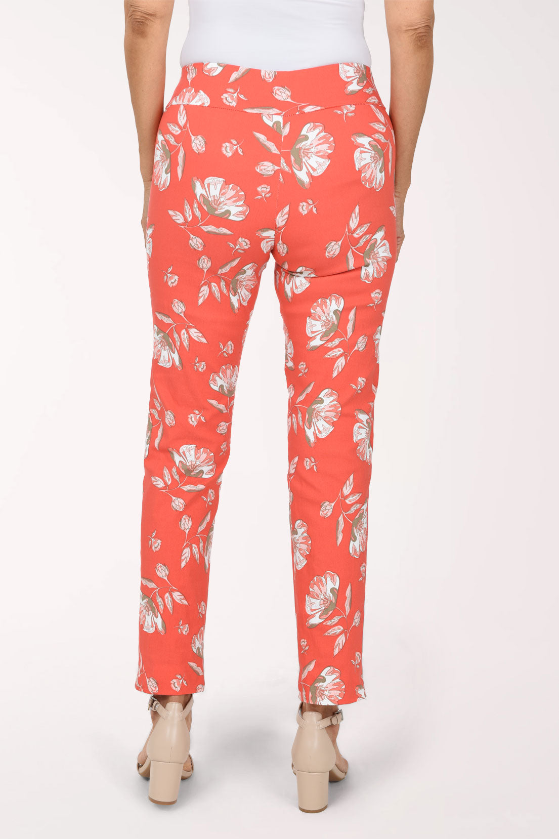 Woman wearing tangerine orange pull on ankle pants with a white floral pattern