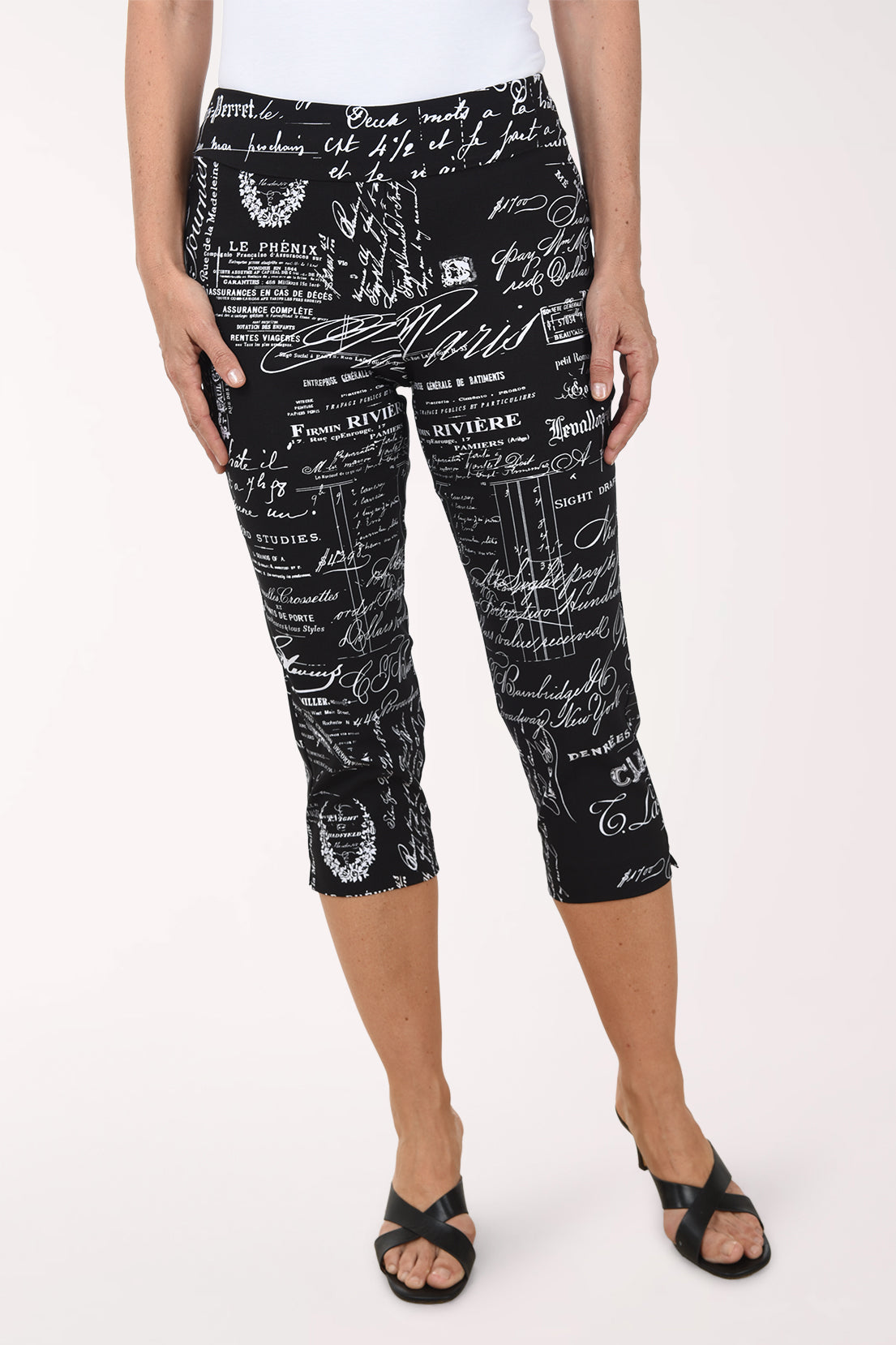 Person wearing black capri pants with white text and graphics on a white background