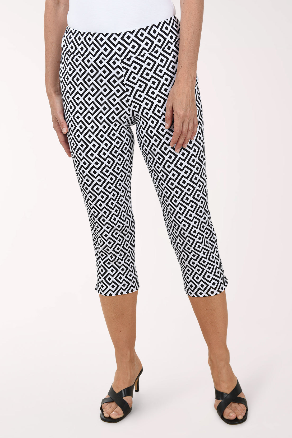 Person wearing black and white patterned capri pants on a white background