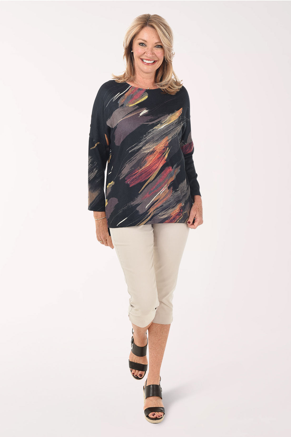 Woman wearing a colorful top and beige pants on a white background