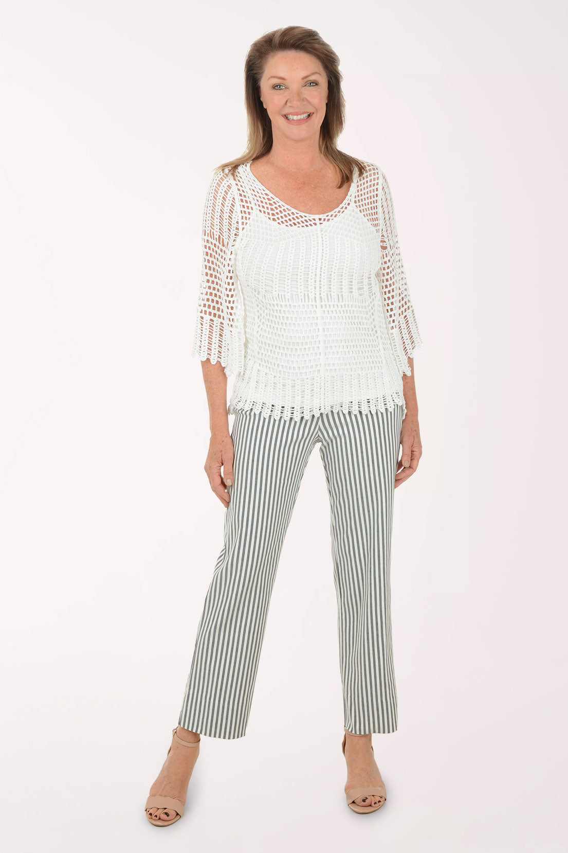 Woman wearing a white top with mesh sleeves and striped pants on a white background