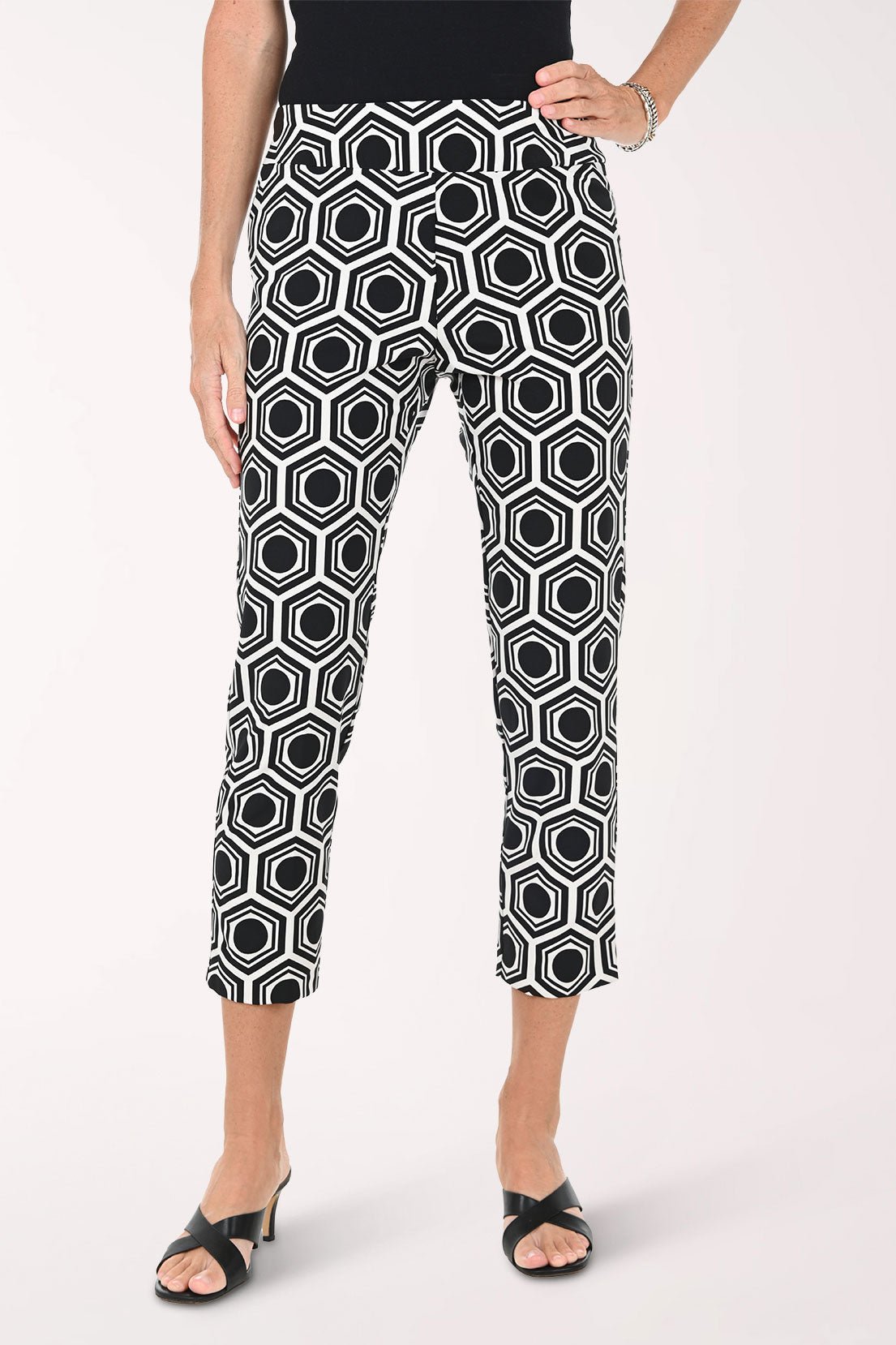 Person wearing black and white geometric patterned pants on a white background