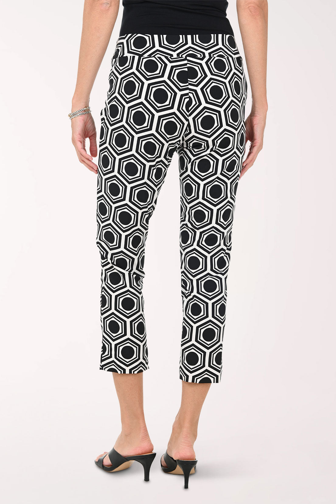 Person wearing black and white geometric patterned pants on a white background