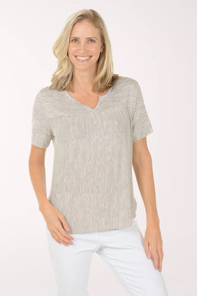 Woman wearing a beige striped shirt and white pants on a white background