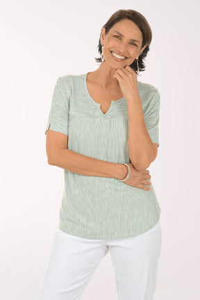 Woman wearing a green striped shirt and white pants on a white background