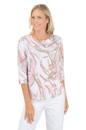 Woman wearing a white blouse with pink and gold abstract pattern on a white background. Second front shot.
