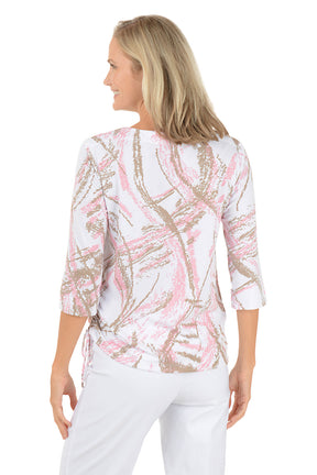 Woman wearing a white blouse with pink and gold abstract pattern on a white background. Back shot.