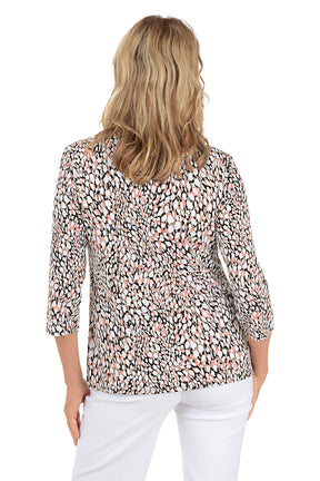 Woman wearing a patterned blouse and white pants on a white background. Back shot.