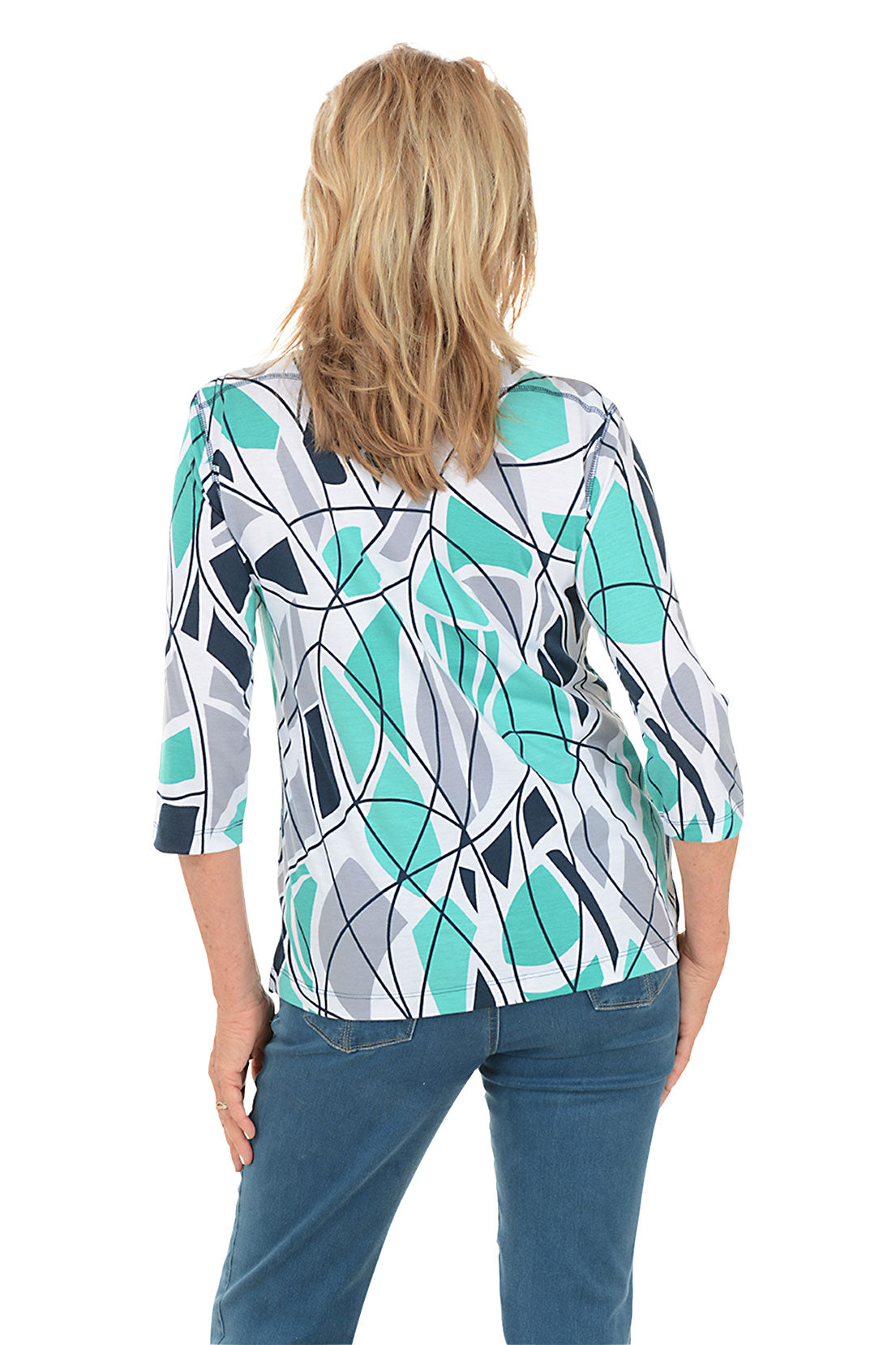 Woman wearing a blue colorful abstract patterned top and white pants on a white background. Back shot.