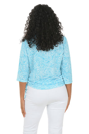 A woman wearing a 3/4 sleeve aqua top with ruched sides. Back shot.