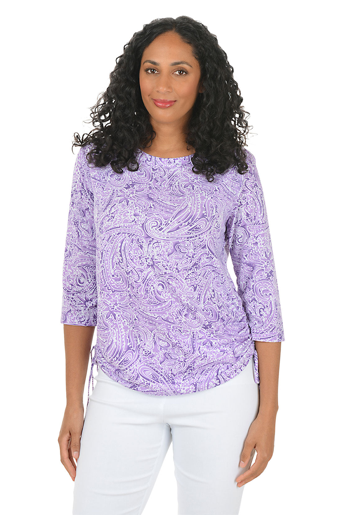 Woman wearing a purple paisley patterned top and white pants on a white background. Second front shot.
